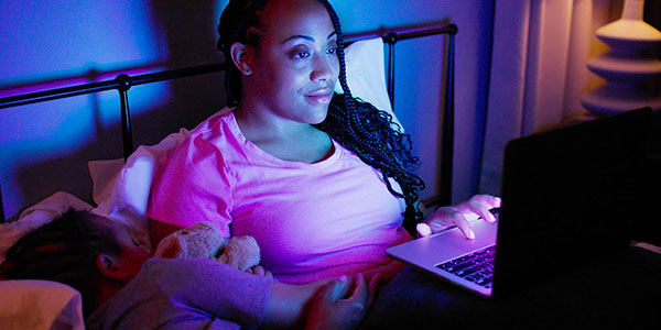 Happy mother studying on her laptop at night